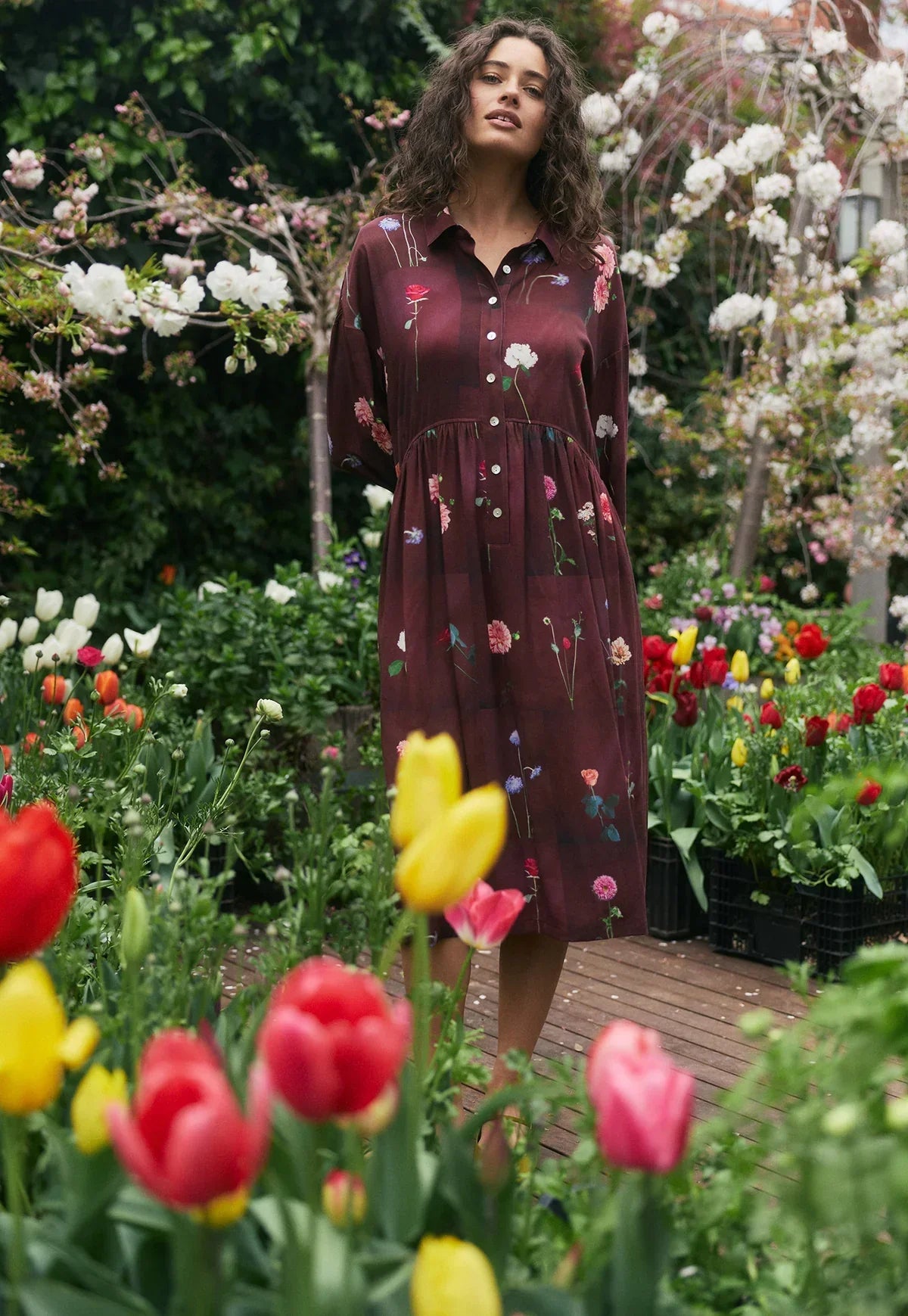 Woman in burgundy floral midi dress among colorful tulips in garden