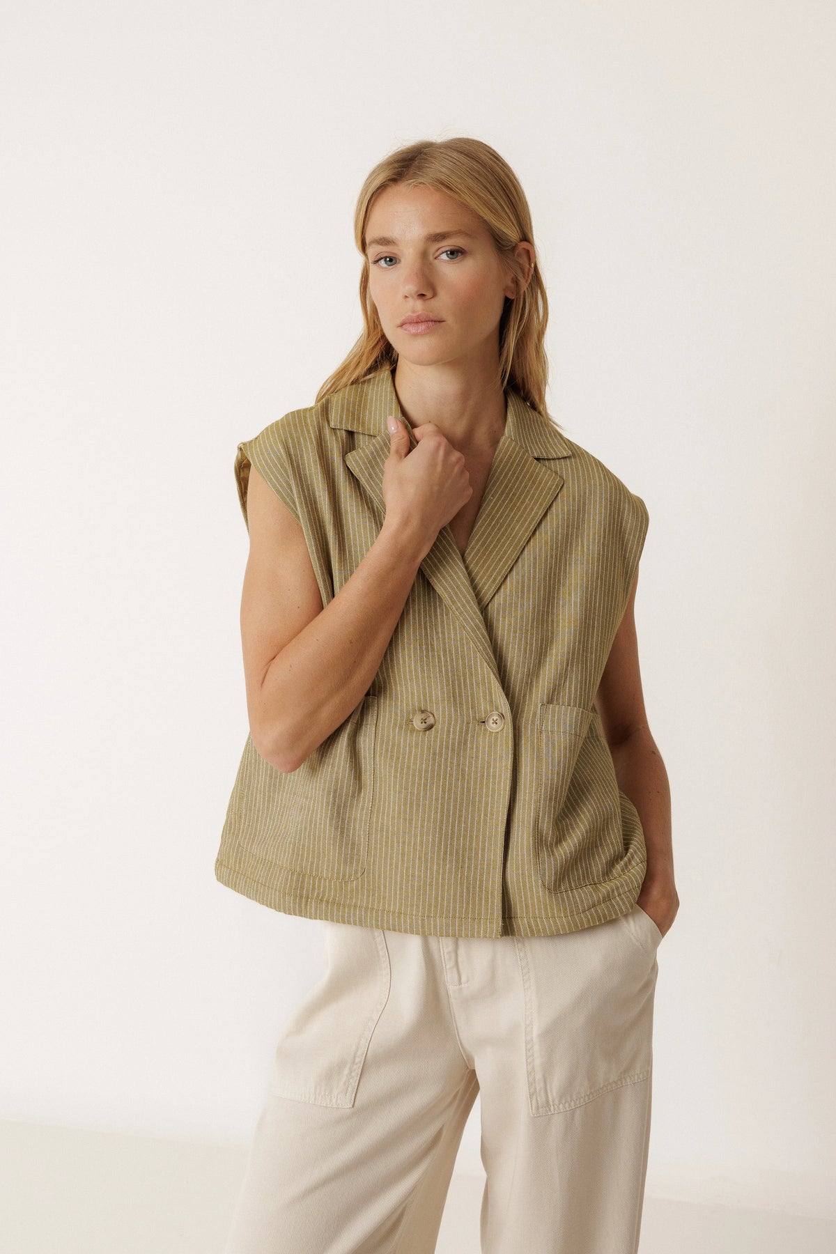 Woman wearing the INDI & COLD Pinstripe Tailored Vest in Khaki with white trousers.