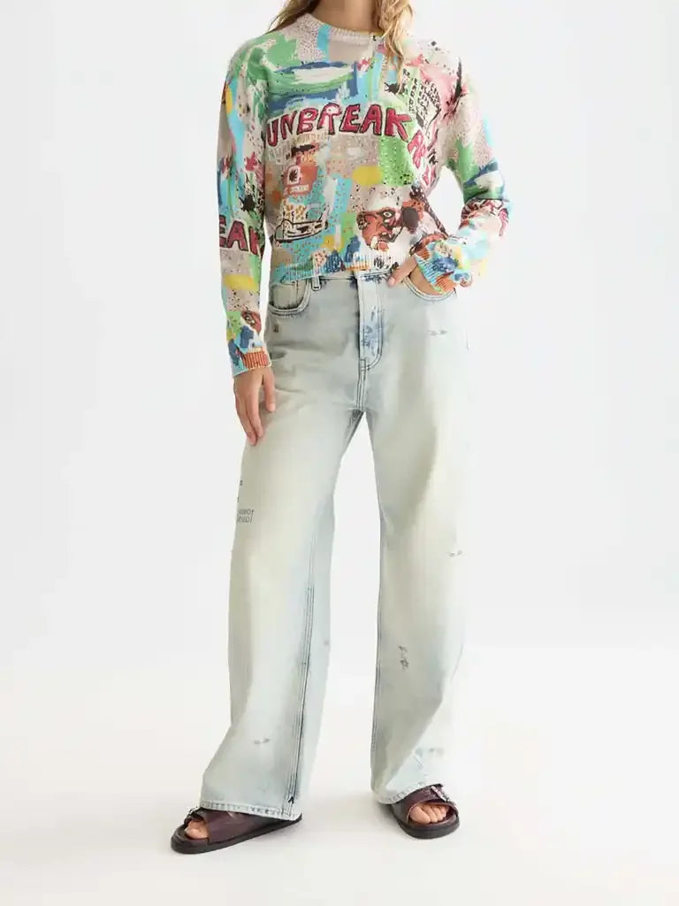 Woman wearing a colorful graphic sweater, light wide-leg jeans, and brown sandals