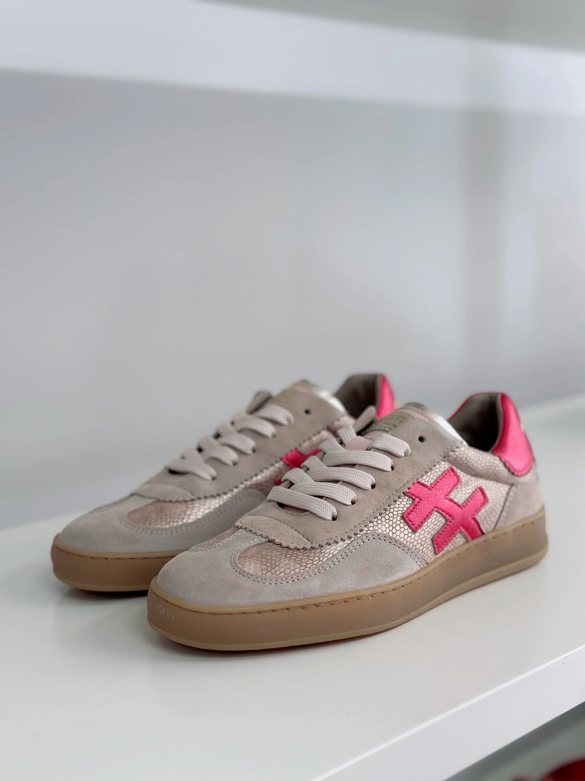 Pair of beige and pink sneakers with a decorative pink logo on the side.