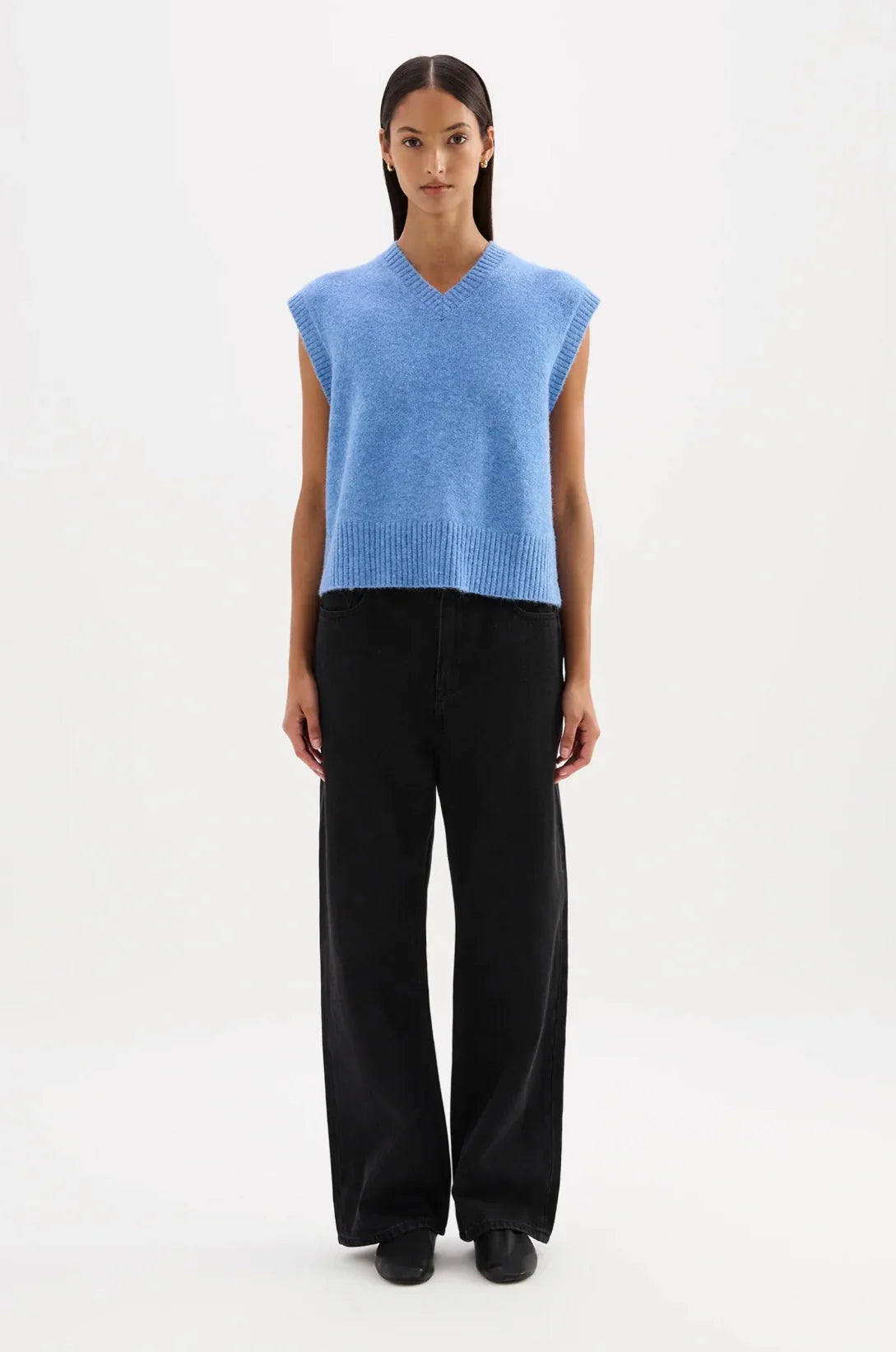 Woman wearing a blue sleeveless knit vest with black wide-leg pants and black shoes
