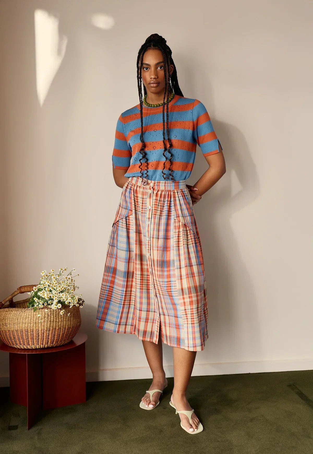 Model wearing NANCYBIRD Rana Knit Tee in Terracotta Stripe with a plaid skirt