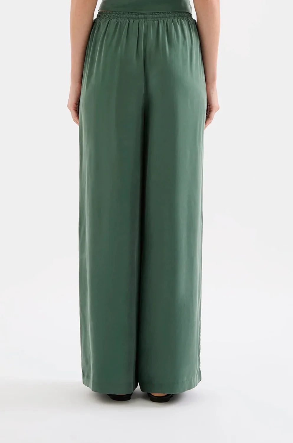 Back view of woman wearing wide leg green trousers with elastic waistband