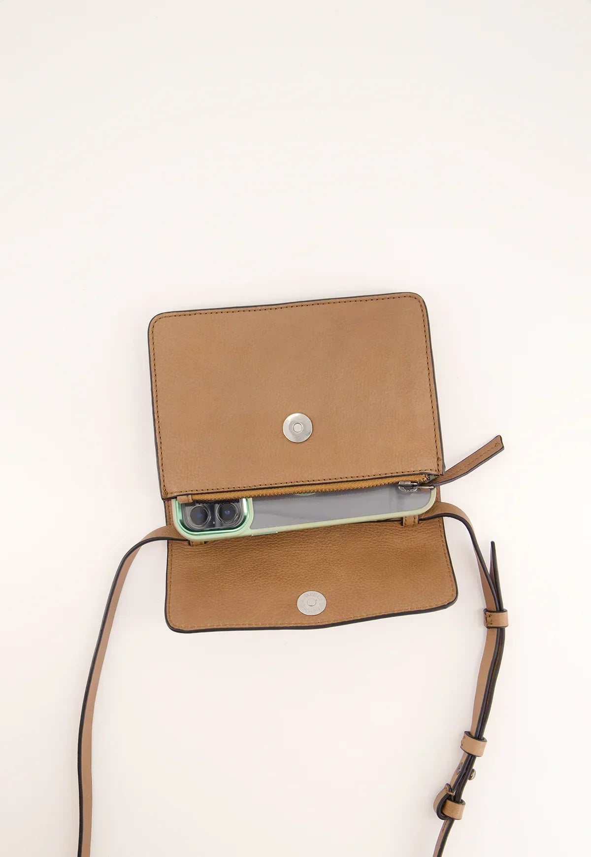 Tan leather crossbody bag with adjustable strap, open to reveal a smartphone inside