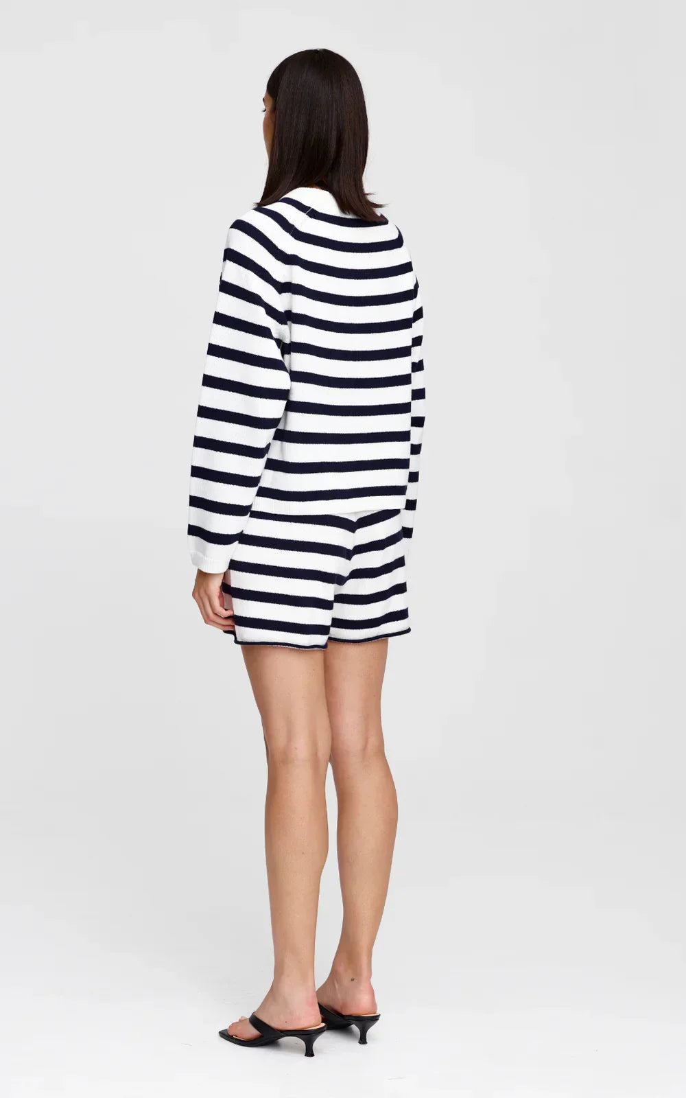 Woman in navy and white striped knit sweater and matching shorts, back view, styled with black heels
