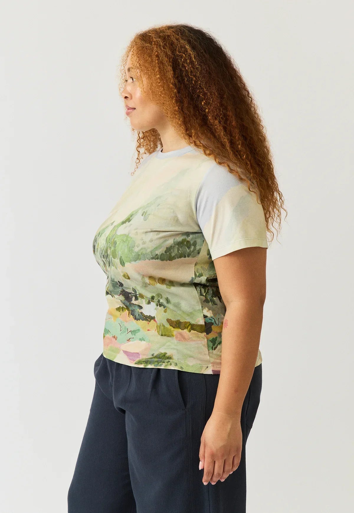 Woman wearing a NANCYBIRD Apollo Tee in Mountain Peak with an abstract landscape print