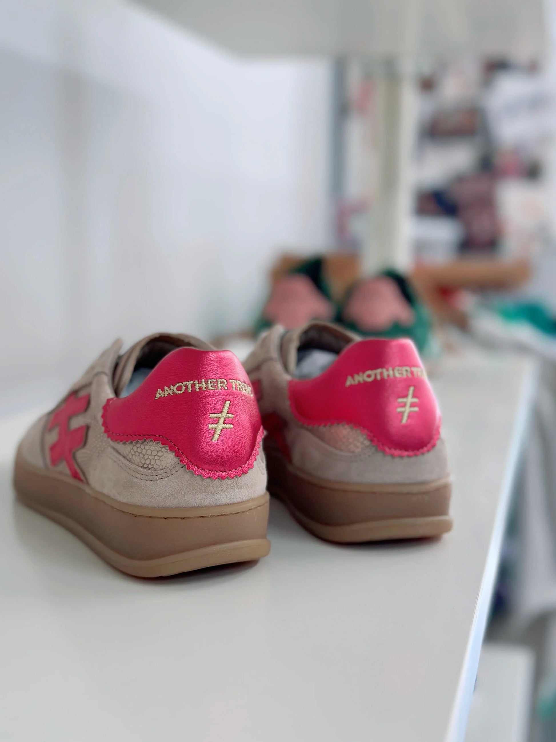 Rear view of beige Another Tree sneakers with bright pink heel accents.