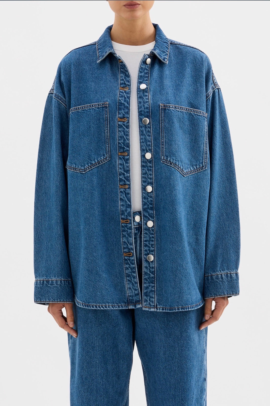 Oversized denim shirt with front pockets, button closure, paired with matching jeans for women's fashion