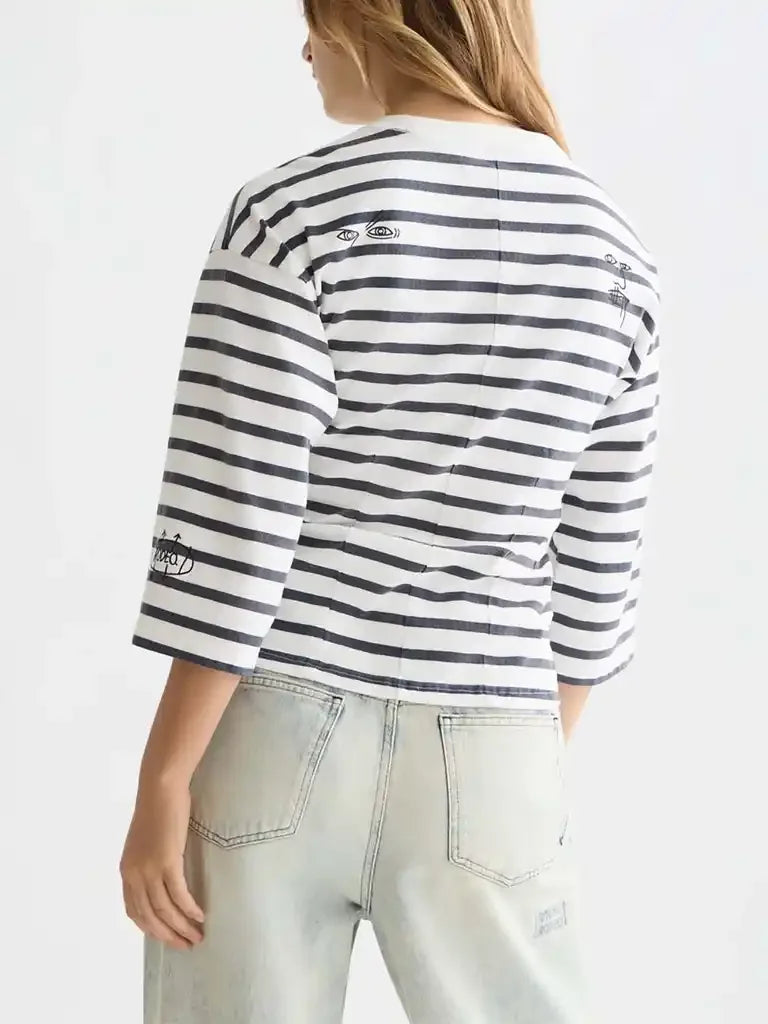 Striped women's top with eye embroidery, paired with light denim jeans