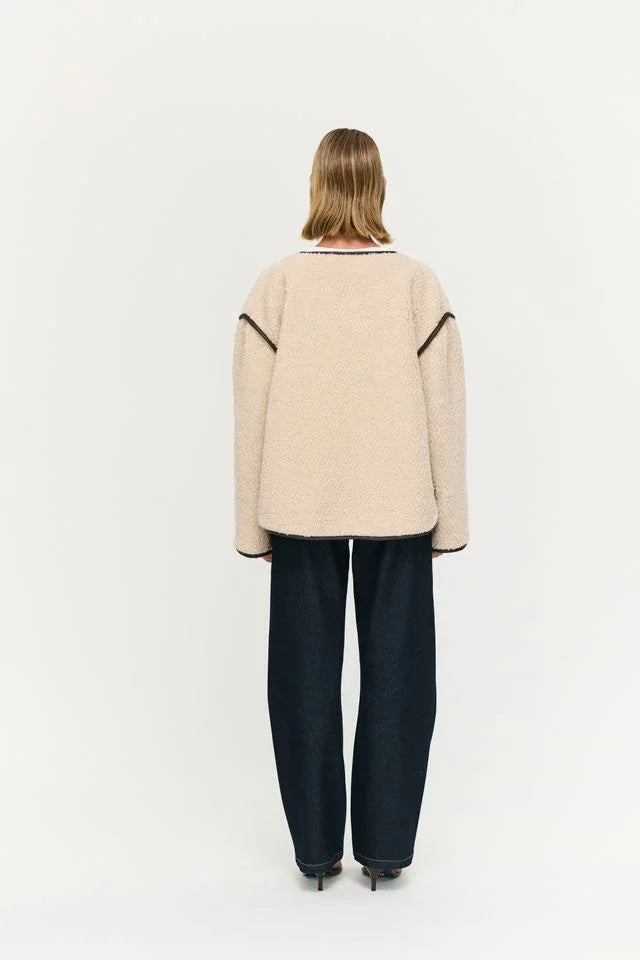 Beige textured sweater with contrast trim, paired with dark wide-leg jeans and heels