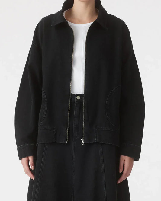 Black denim jacket with zipper and pockets, paired with white top and black skirt