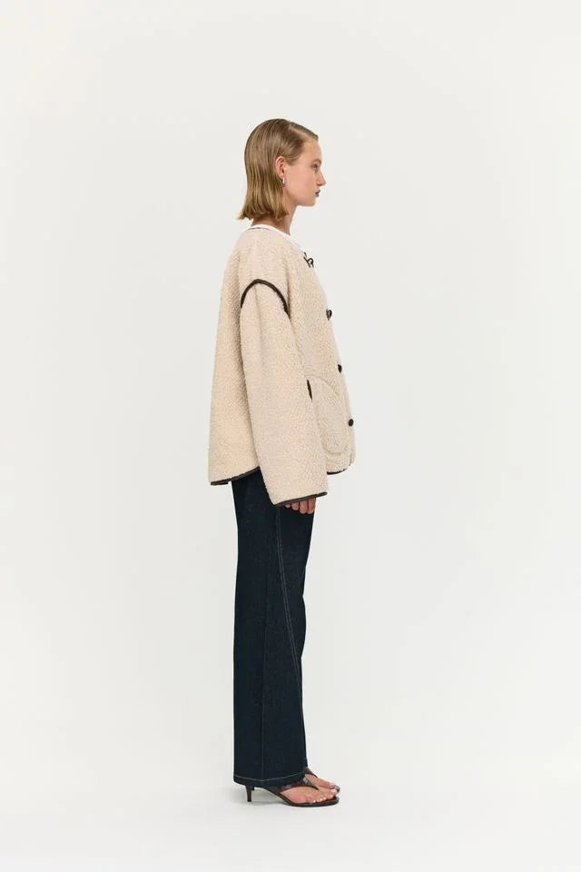 Cream teddy coat with black trim, styled with dark wide-leg jeans and black heels for women's fashion