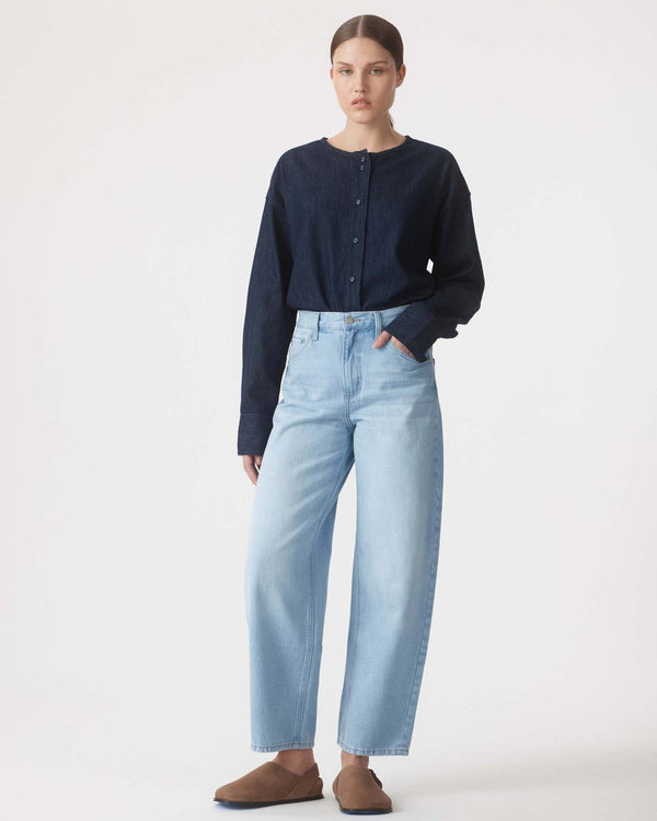 Person wearing a dark blue shirt and light blue jeans on a white background