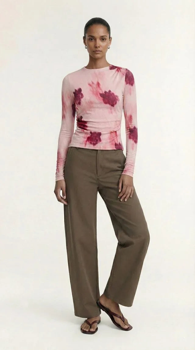 Woman wearing a pink tie-dye long sleeve top and olive green wide-leg trousers.