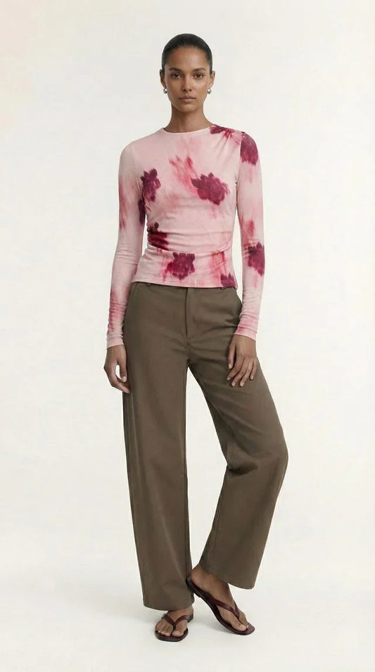 Woman wearing a pink tie-dye long sleeve top and olive green wide-leg trousers.