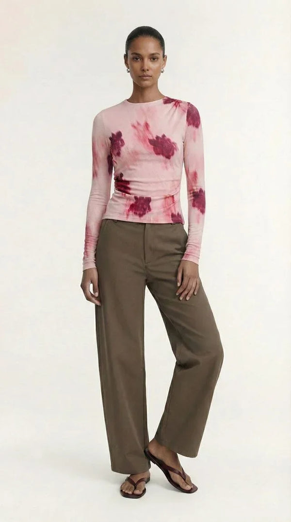 Woman wearing a pink tie-dye long sleeve top and olive green wide-leg trousers.