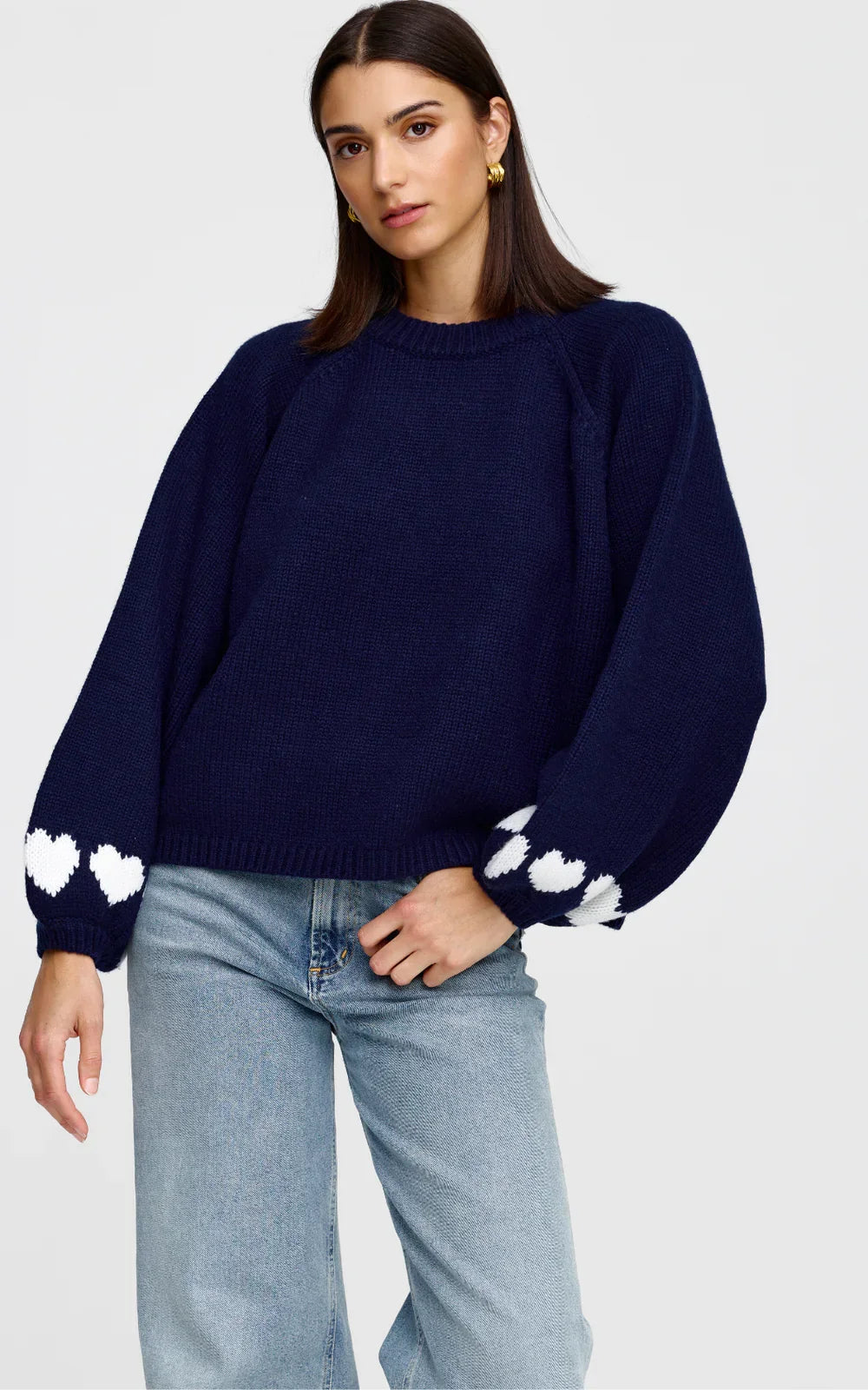 Navy blue knit sweater by Kinney with white heart details on sleeves, paired with light wash jeans