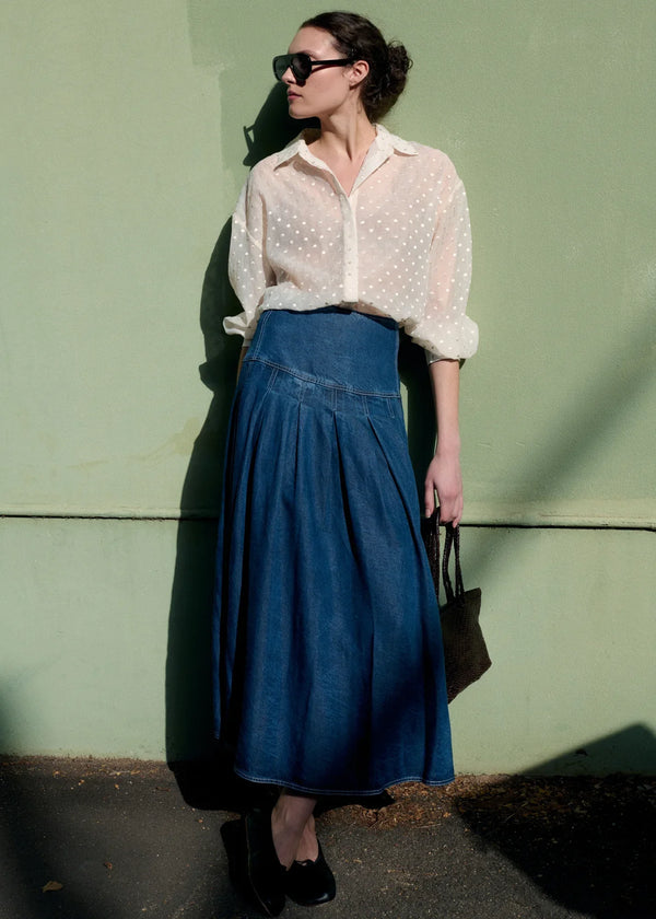 Woman wearing STAPLE THE LABEL Roma Chambray Midi Skirt and a sheer white blouse.