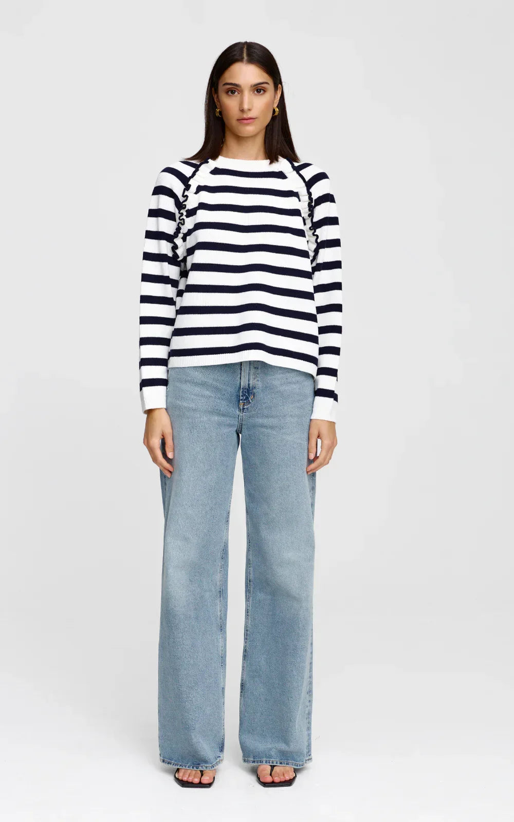 Woman wearing Kinney Chloe Jumper with navy and white striped sweater with ruched sleeves and light wash wide-leg jeans