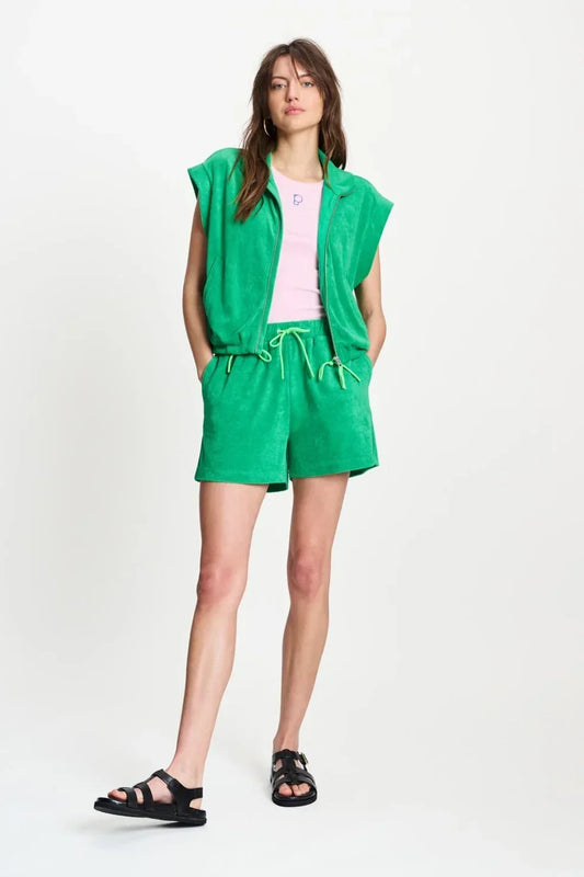 Woman wearing a green sleeveless zip-up top and matching green shorts with black sandals.