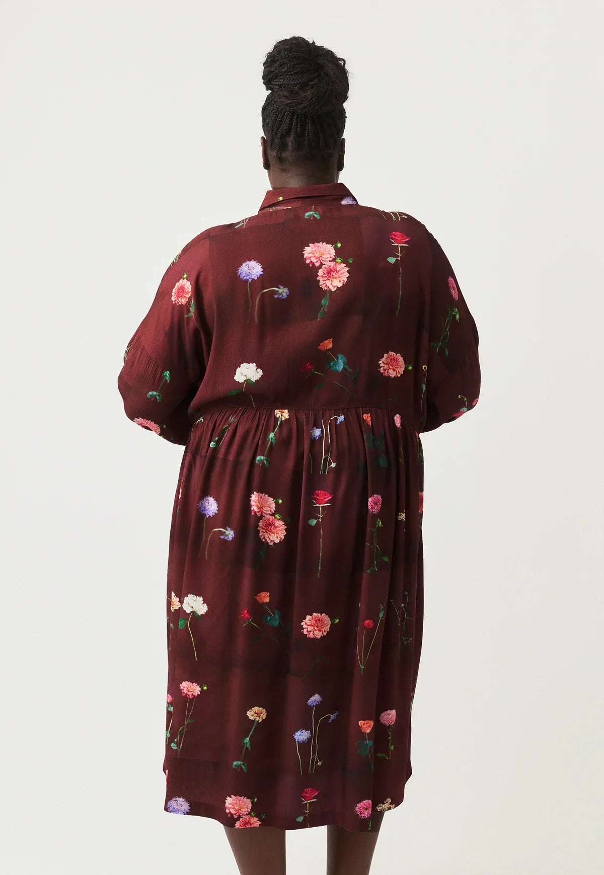 Back view of woman wearing burgundy floral print shirt dress with puff sleeves and elastic waist