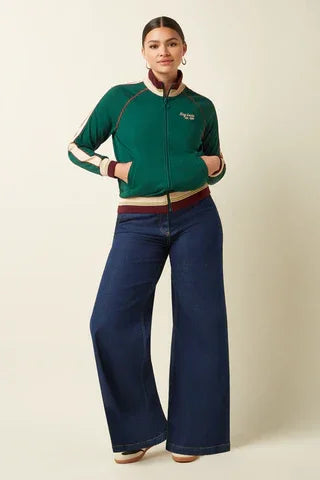 Woman wearing a green zip-up jacket and wide-leg high-waisted blue jeans
