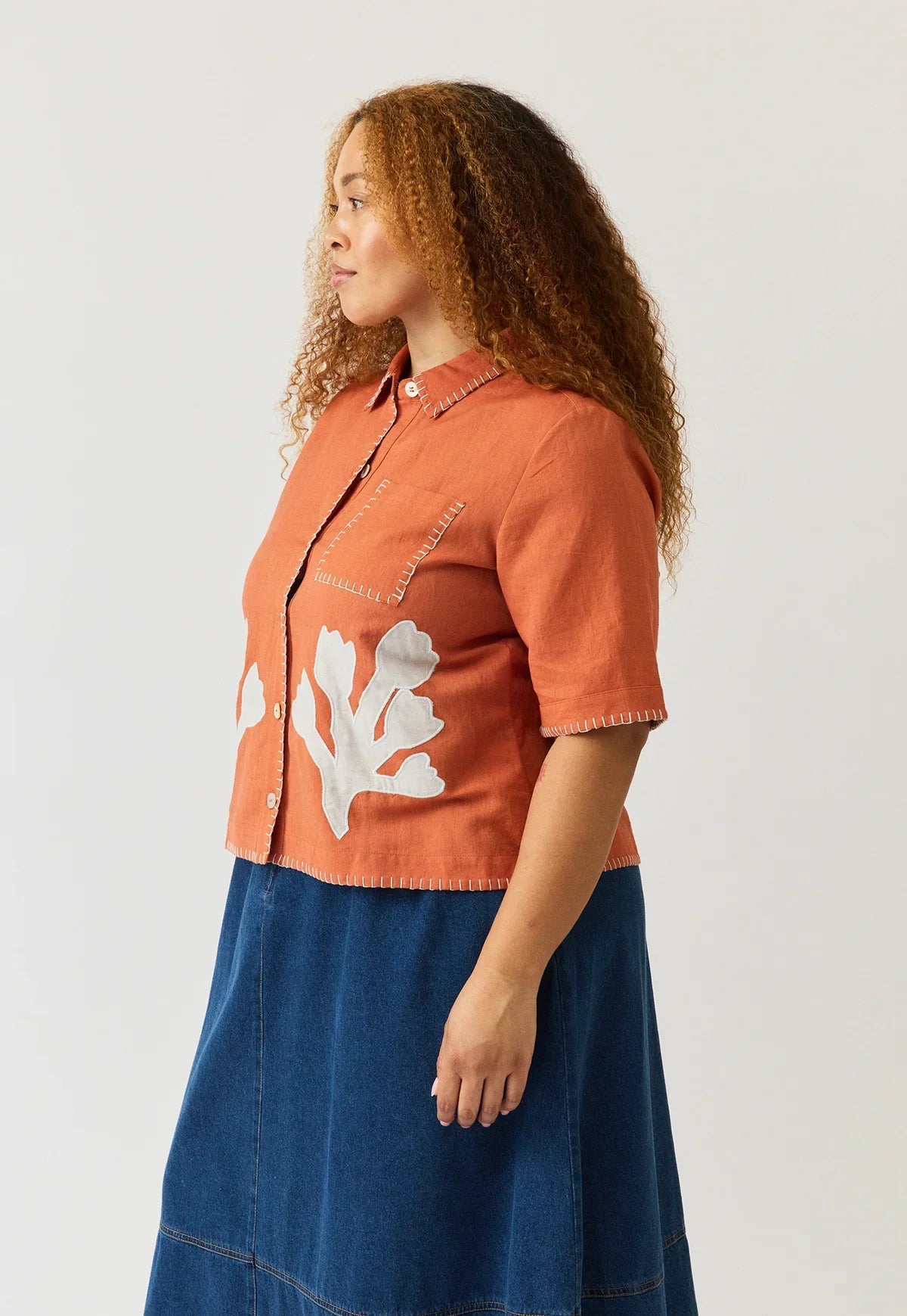 Woman wearing a NANCYBIRD Summer Shirt in Blossom Appliqué with a denim skirt