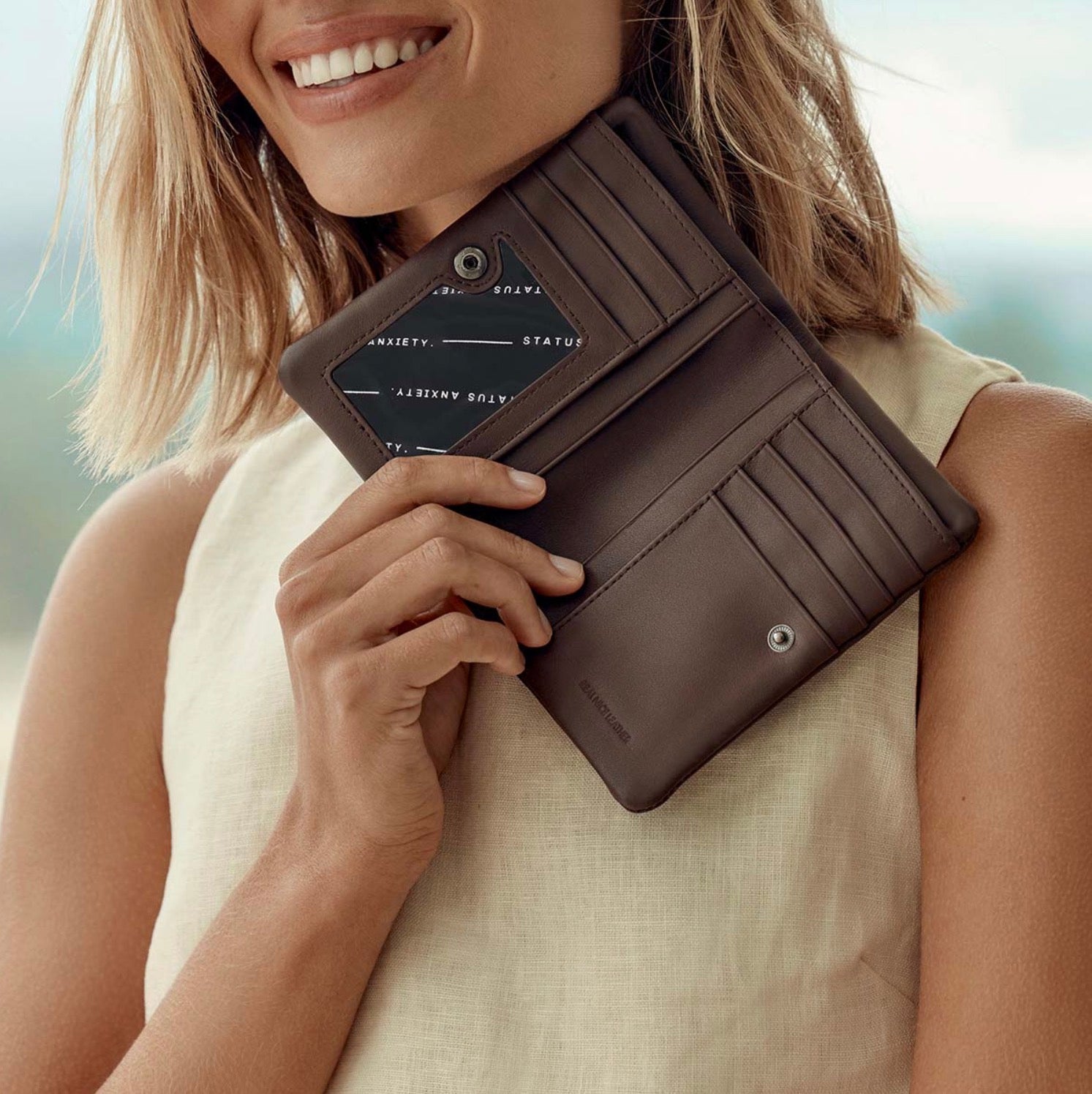 Woman holding brown leather wallet with card slots and ID window, stylish everyday accessory