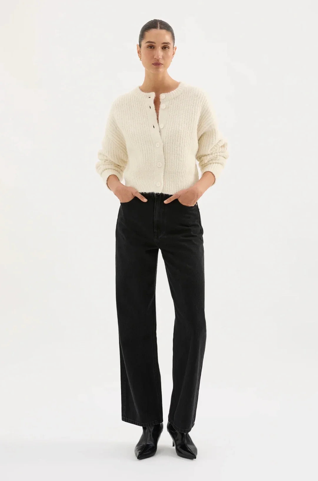 Woman wearing cream knit cardigan with black high-waisted jeans and black boots