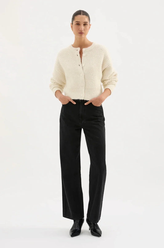 Woman wearing cream knit cardigan with black high-waisted jeans and black boots