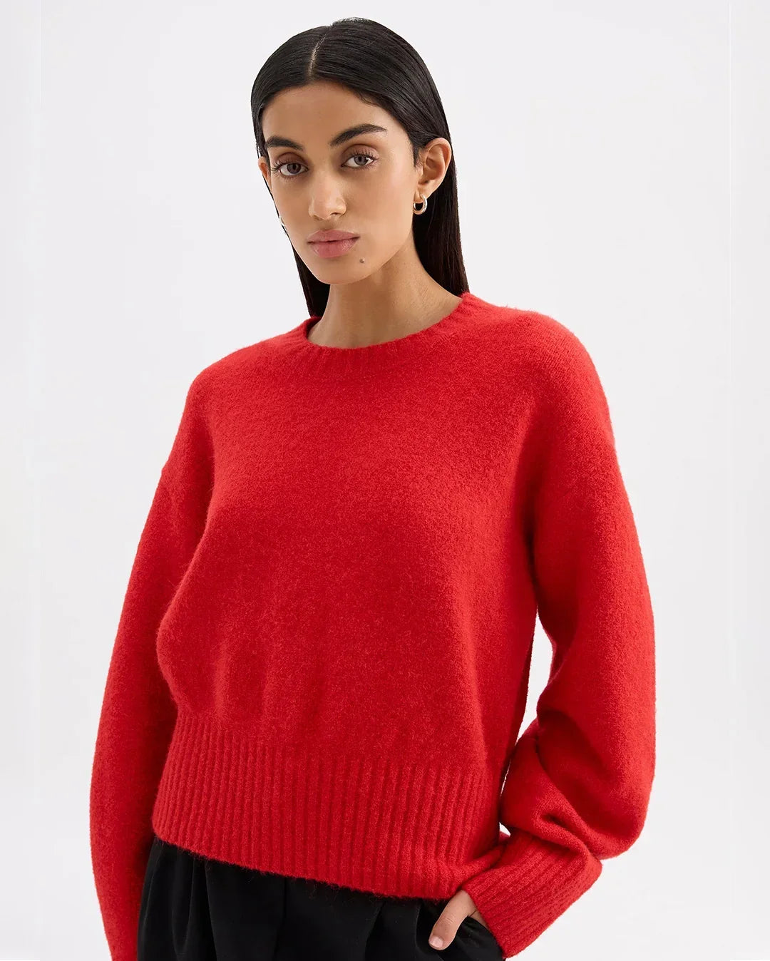 Woman wearing a vibrant red fuzzy knit sweater and black trousers.