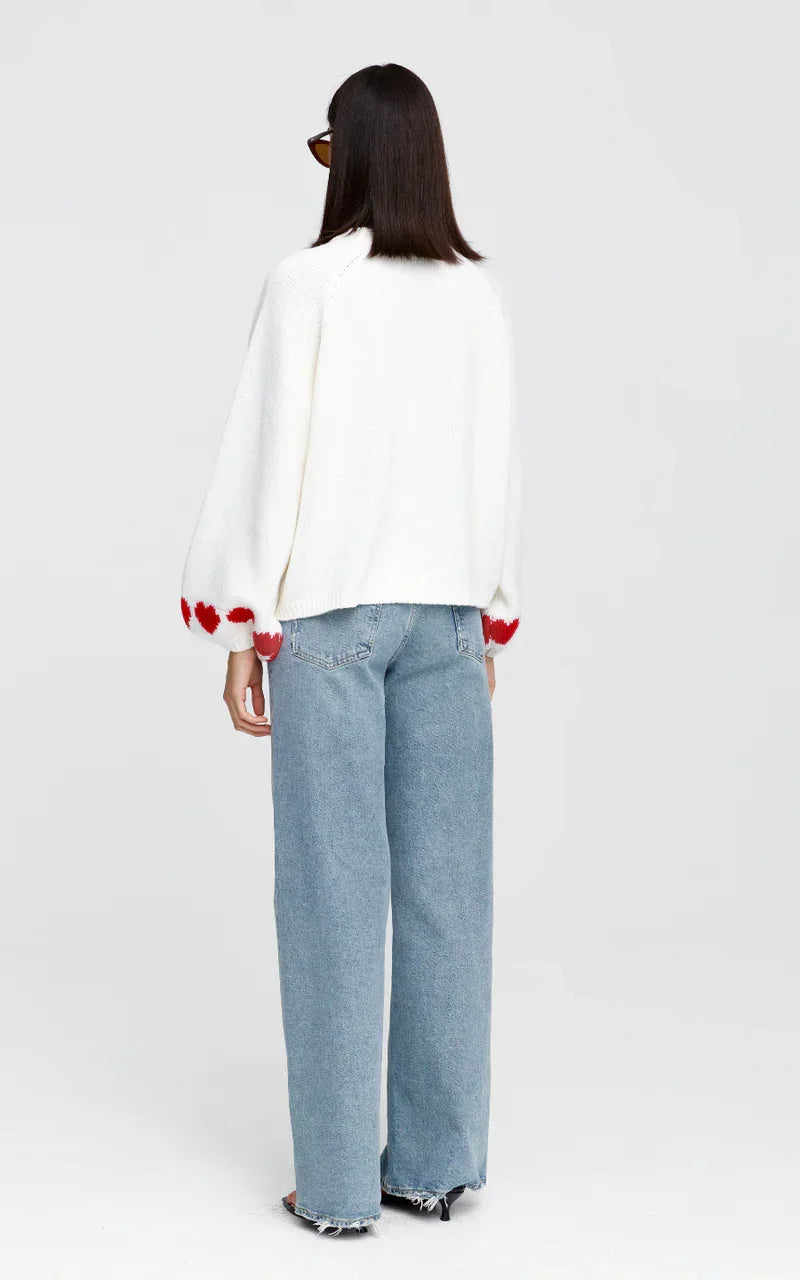 Woman wearing white heart-patterned sweater and wide-leg jeans, back view