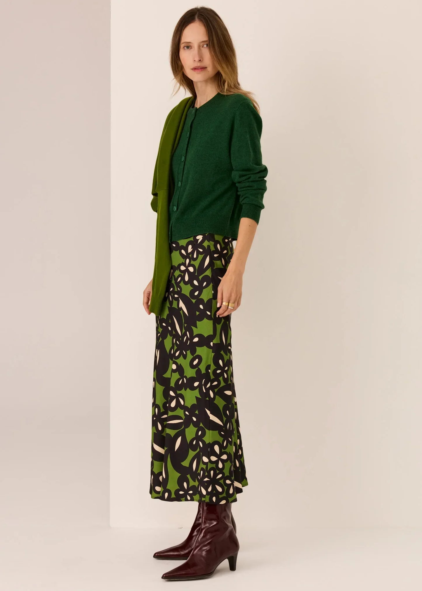 Woman in green cardigan, floral skirt, and burgundy boots — women's fashion outfit