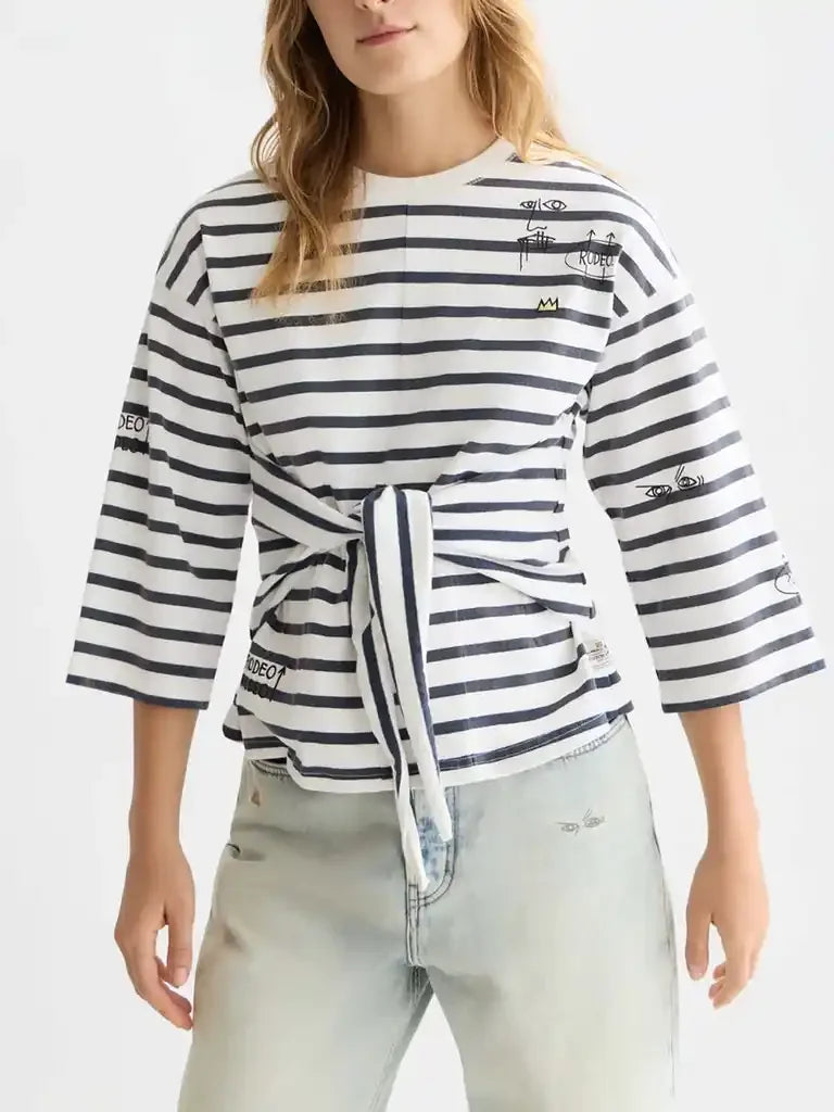 Striped women's tie-front top with graphic details, paired with light wash jeans