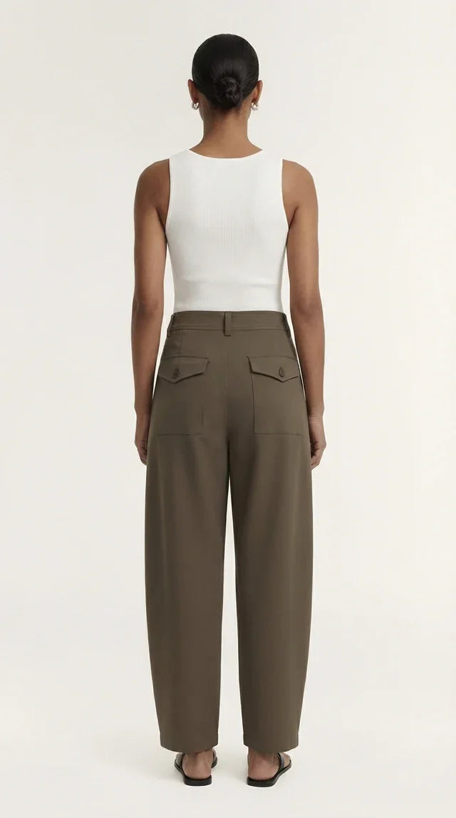 Woman wearing high-waisted olive green wide-leg trousers and a white sleeveless top.
