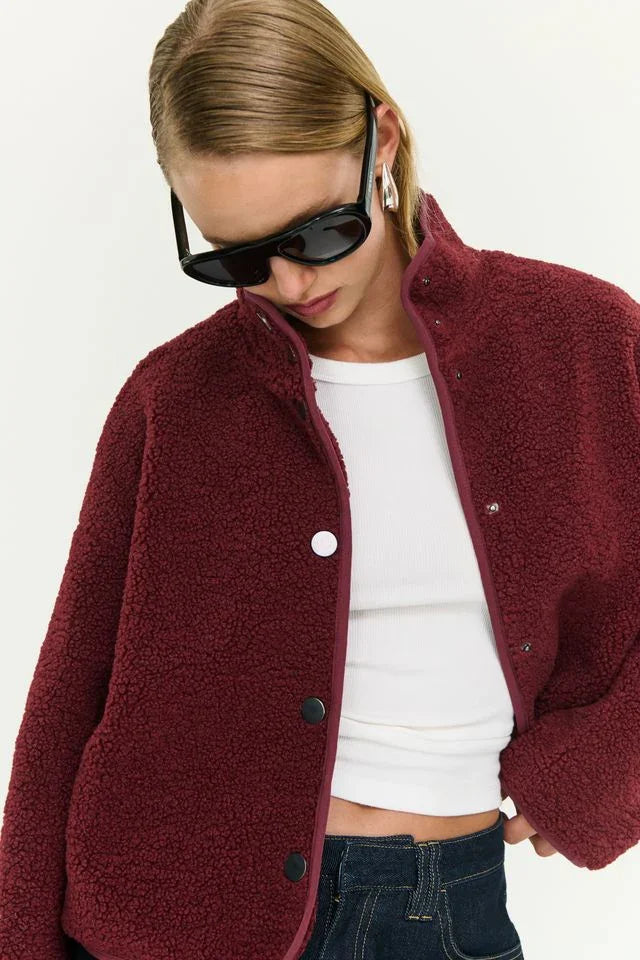 Burgundy teddy jacket with white buttons, styled with white top and denim, modern women's fashion