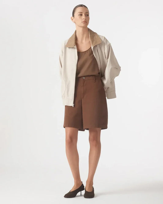 Woman wearing Nobody Denim Rowan Bermuda Shorts in coffee with a beige jacket and brown heels.