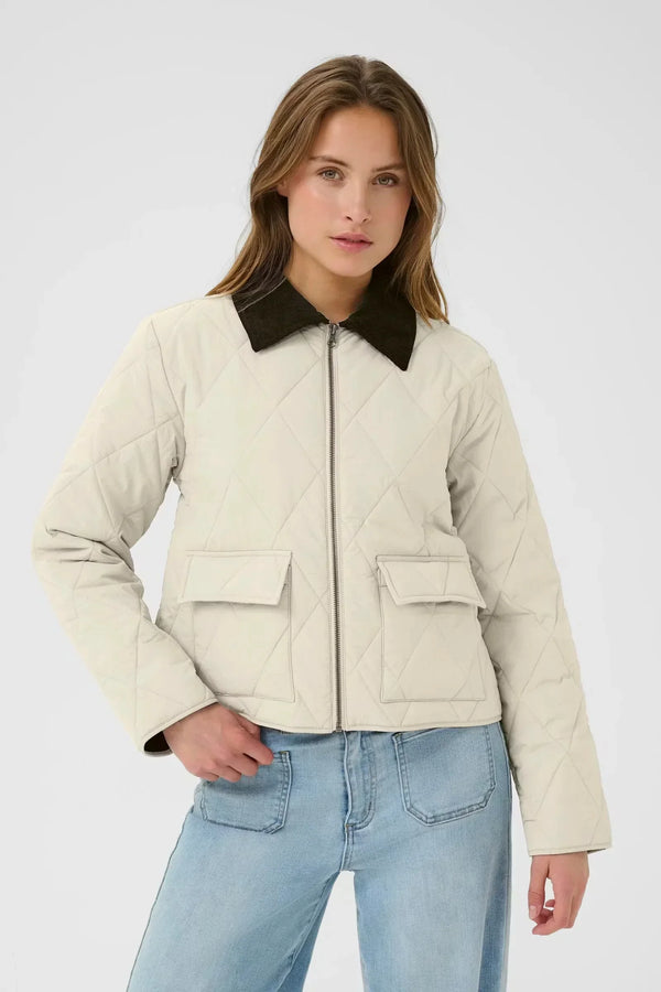 Woman wearing a cream quilted jacket with dark collar and light wash jeans