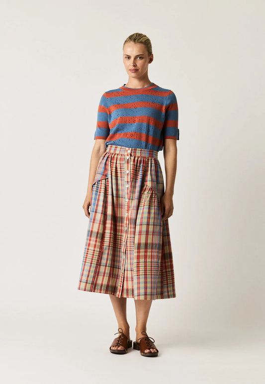 Woman wearing a NANCYBIRD Acacia Skirt in Coast Check and a blue and orange striped knit top.