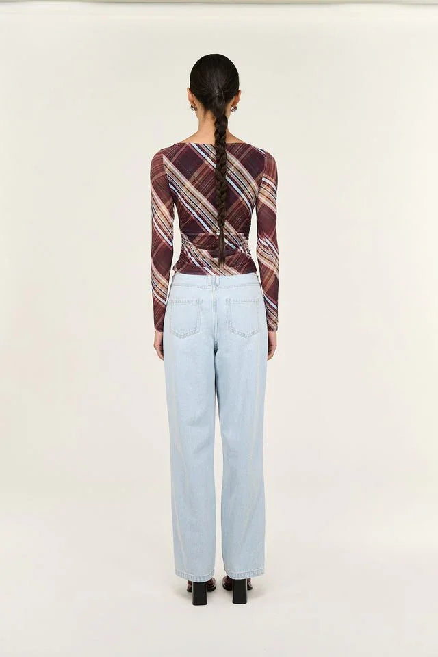 Woman wearing plaid long-sleeve top and light blue jeans, back view
