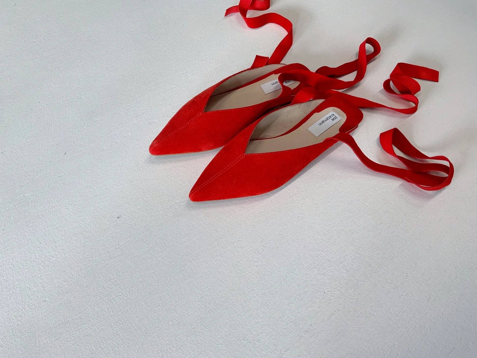 Red suede pointed-toe ballet flats with long tie-up ankle straps.