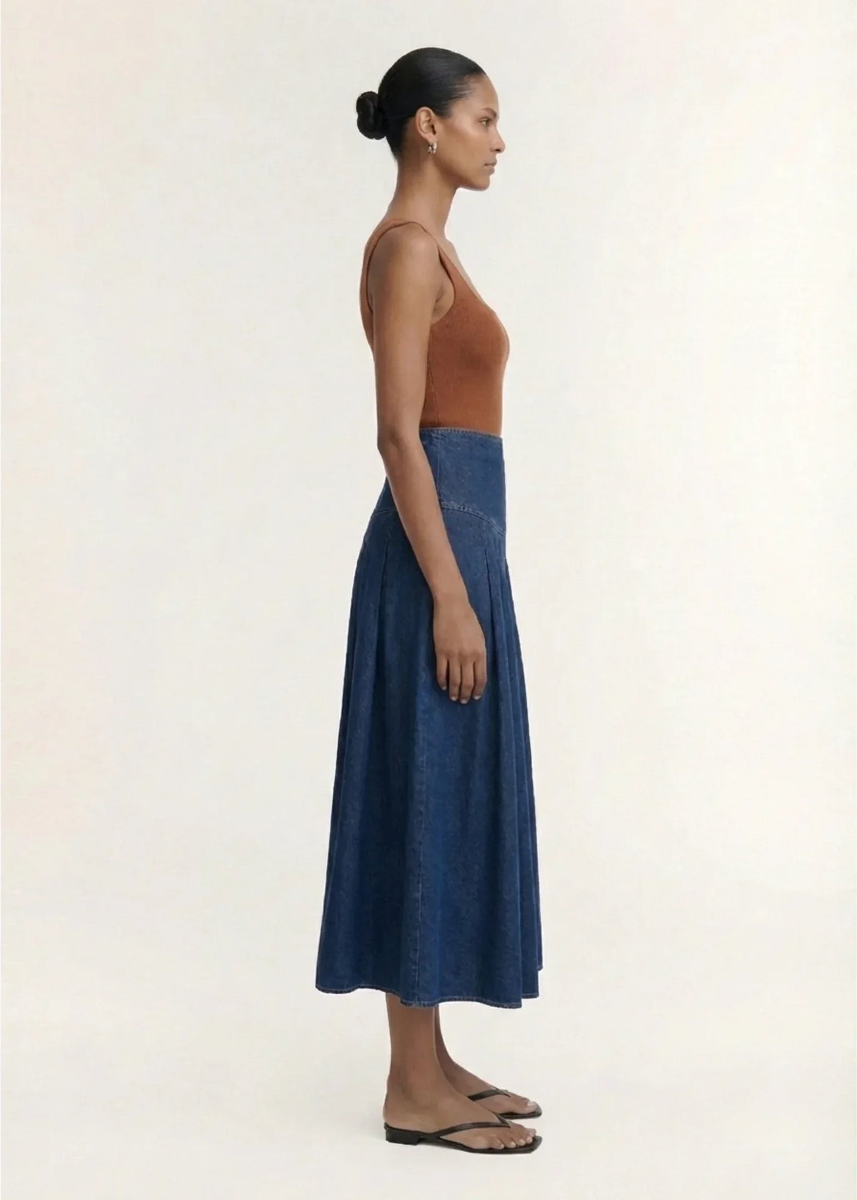 Side view of a woman wearing a STAPLE THE LABEL Roma Chambray Midi Skirt and brown tank top.