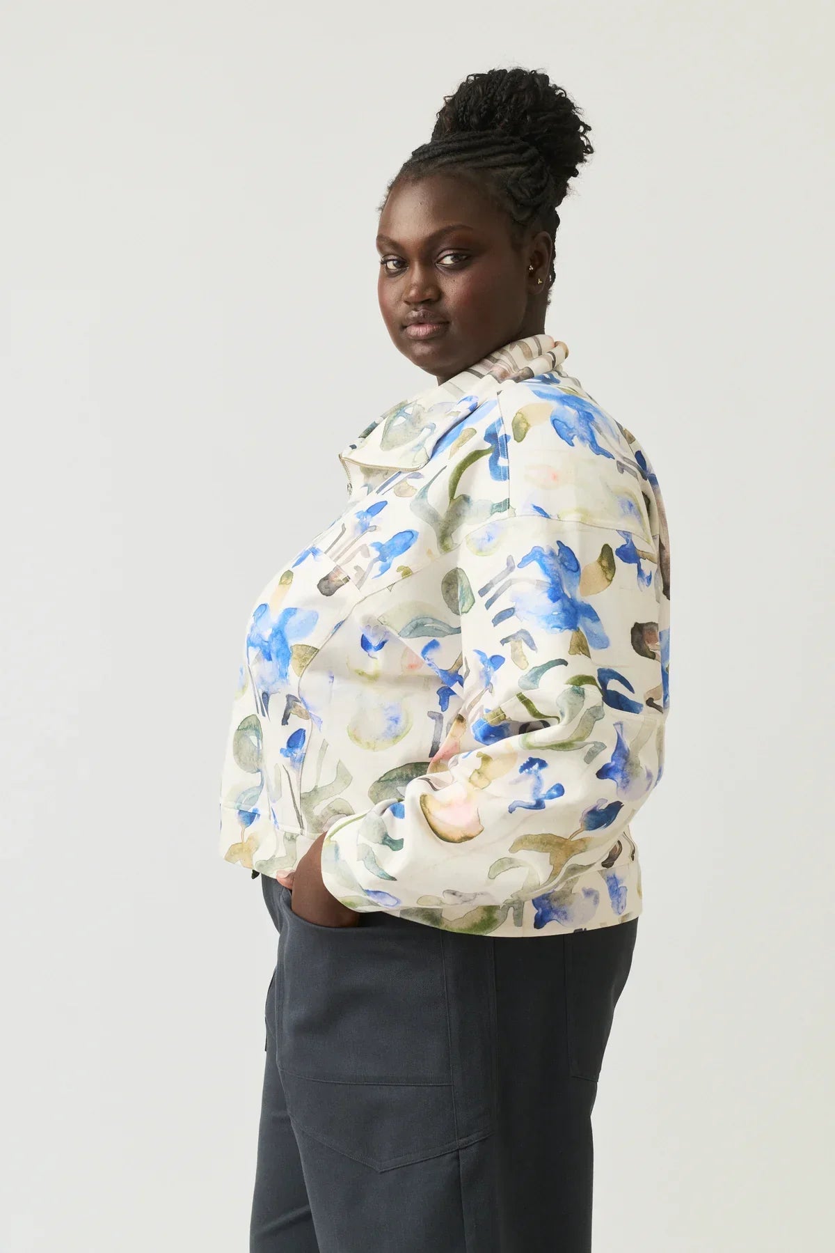 Woman wearing a watercolor floral print jacket and dark trousers, side profile view