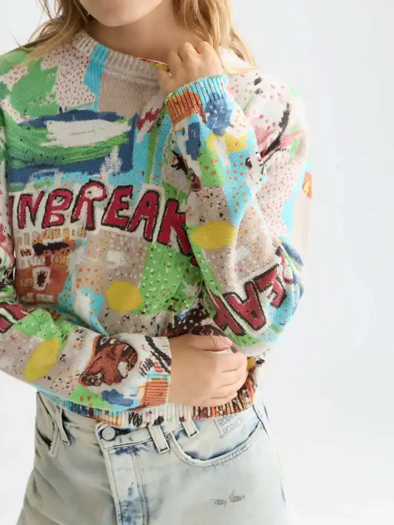 Woman wearing colorful graphic knit sweater with text and light denim jeans
