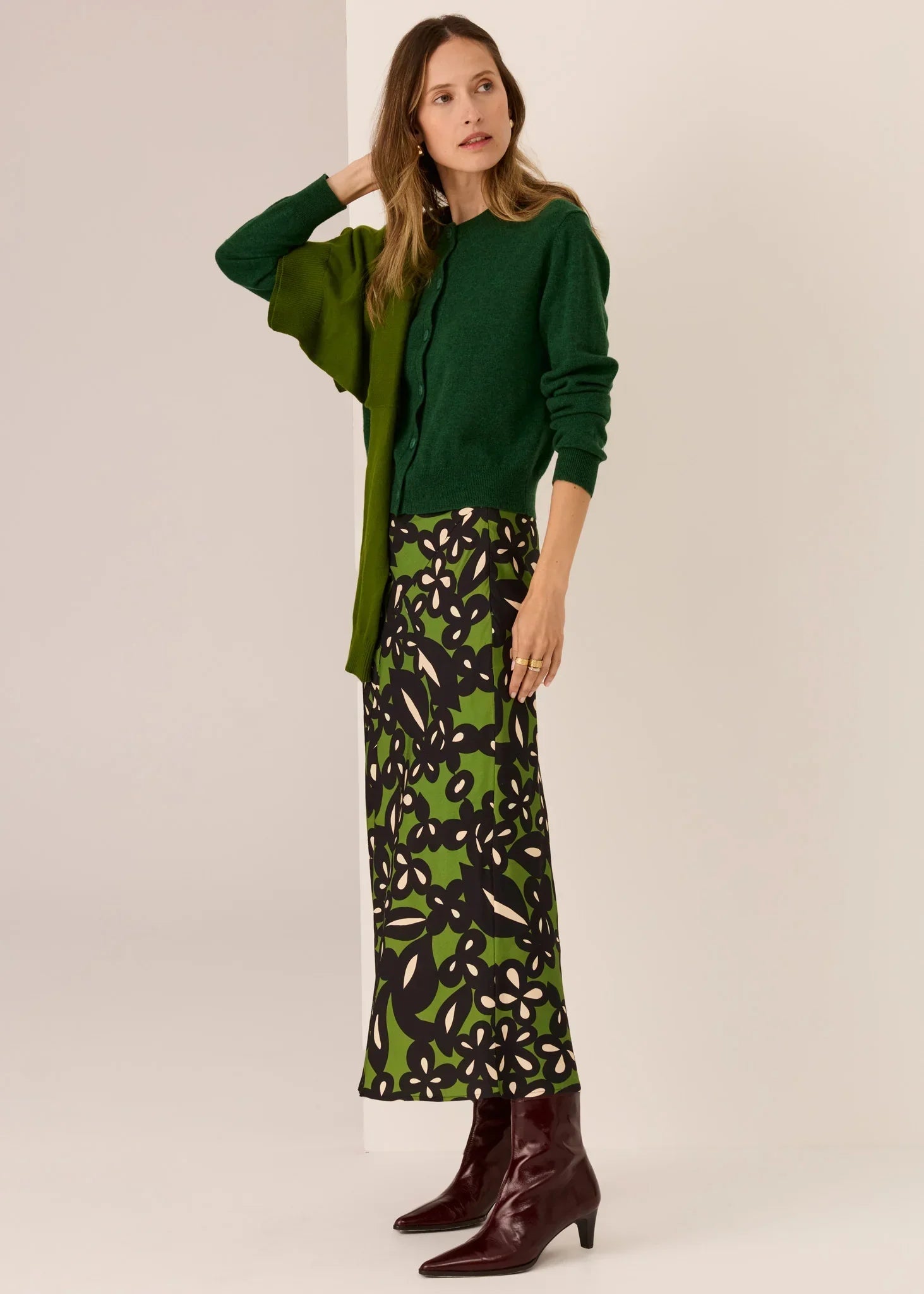 Woman in green cardigan, floral skirt, and burgundy boots — women's fashion