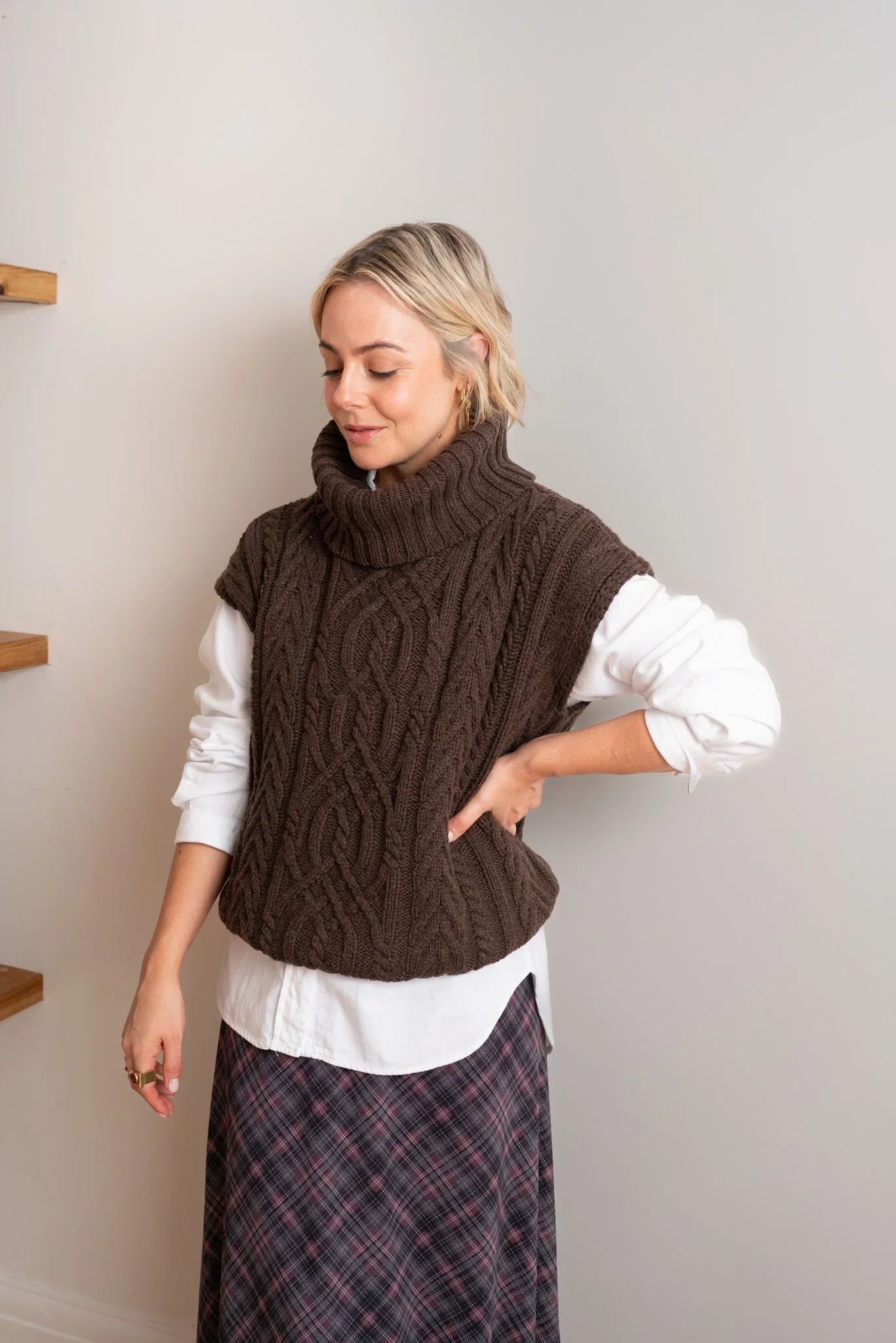 Brown cable knit vest over white shirt with plaid skirt, stylish women's fashion