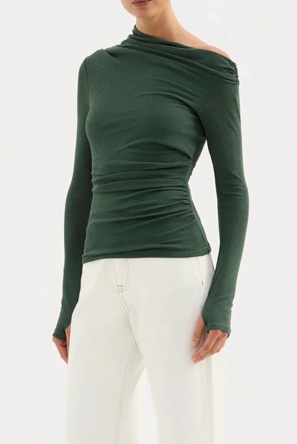 Woman wearing a fitted green long sleeve off-shoulder top with white pants