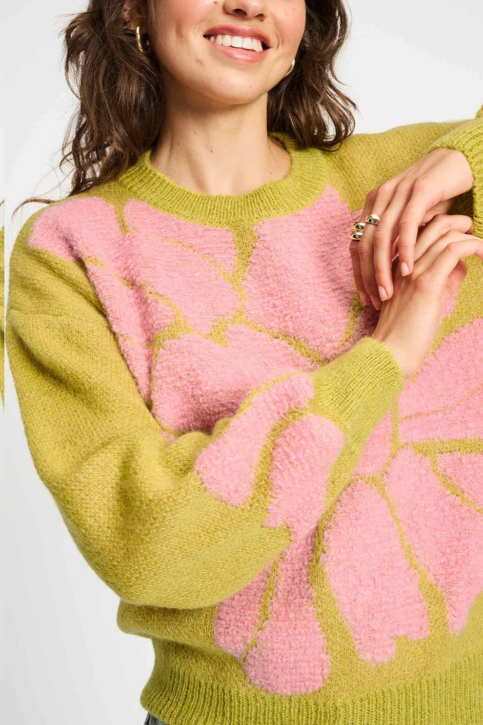 Woman wearing a green knit sweater with bold pink floral pattern, fashion clothing detail