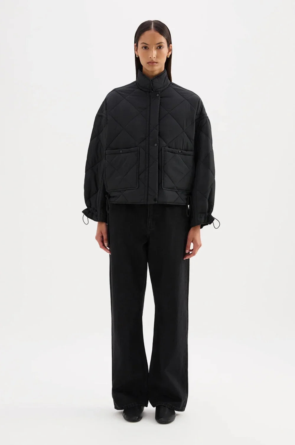 Black quilted jacket with front pockets and drawstring cuffs paired with wide-leg pants