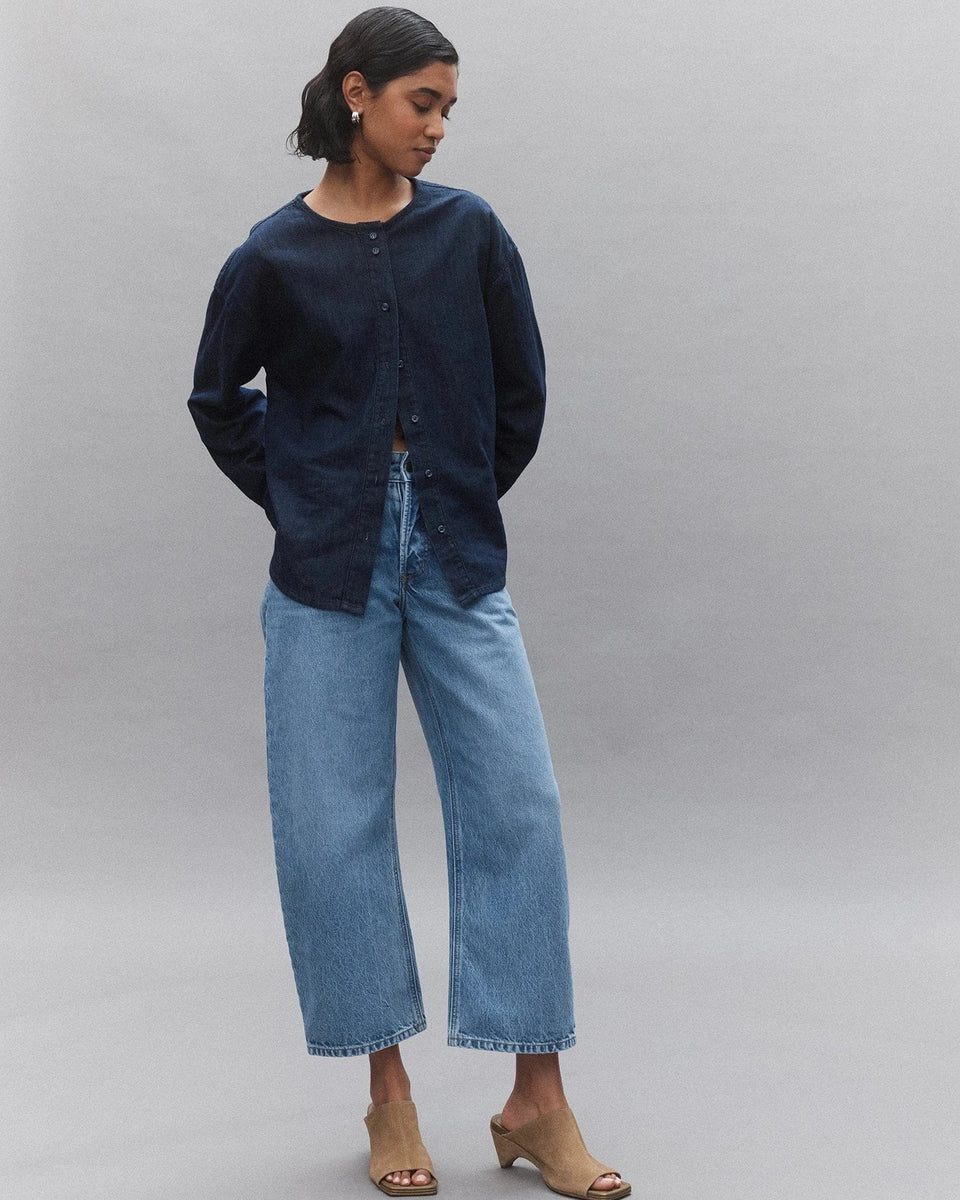 Woman wearing navy button-up shirt, wide-leg denim jeans, and beige heeled sandals
